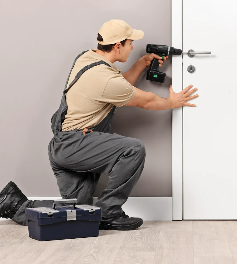 fachowiec instalujący klamkę za&nbsp;pomocą wkrętarki