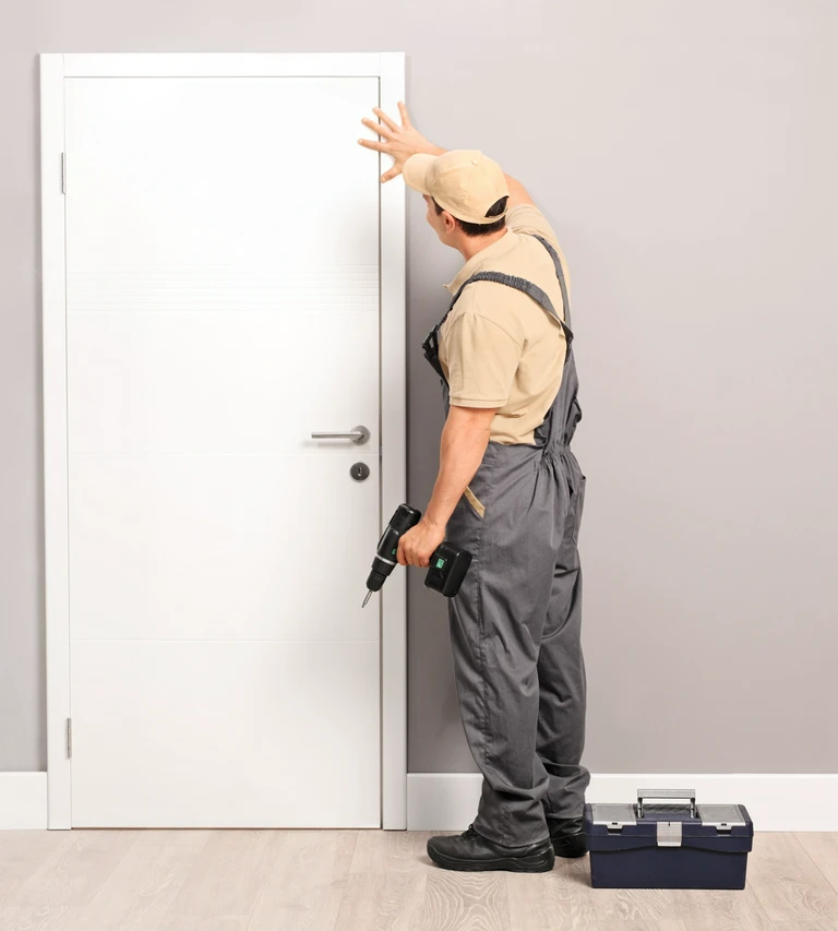 Instalator drzwi pracujący przy ościeżnicy w&nbsp;mieszkaniu